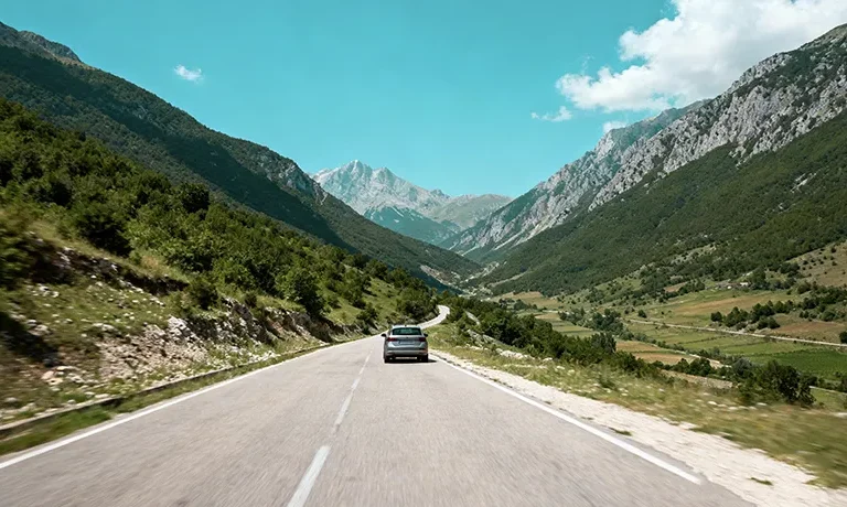 The Complete Driving Guide For International Tourists In Albania 2 - Car Rent in Albania Scenic mountain road in Albania with rental car driving through valley with green hillsides