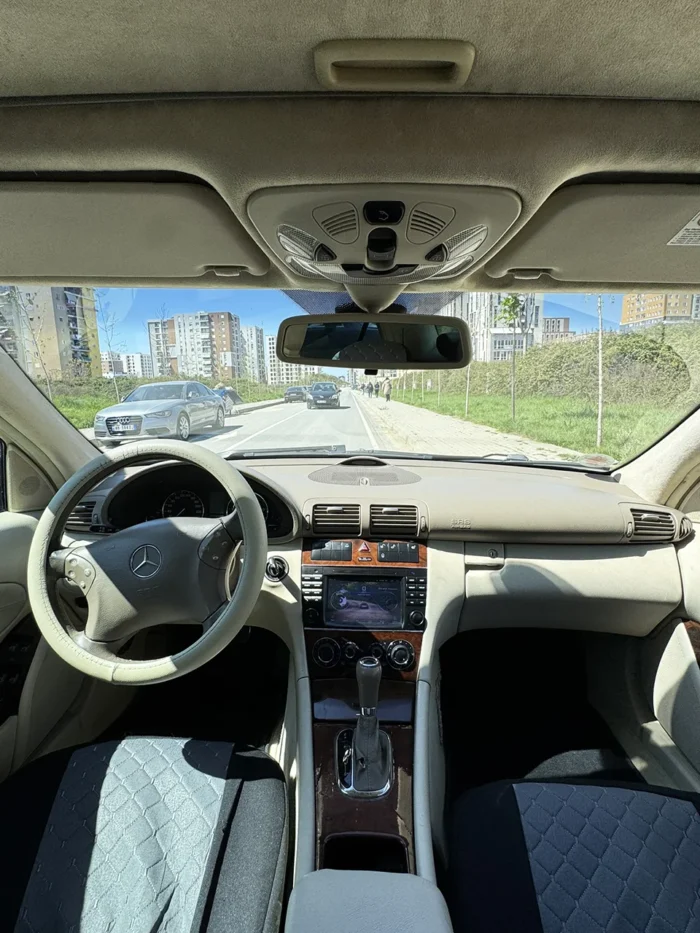 Interior of Mercedes C-Class 2007 with beige dashboard, steering wheel and automatic gear selector