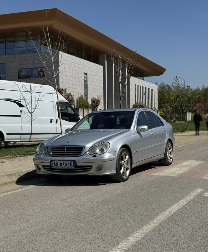 Silver Mercedes C-Class 2007 1.8 petrol automatic sedan front angle view parked by a modern building in Tirana