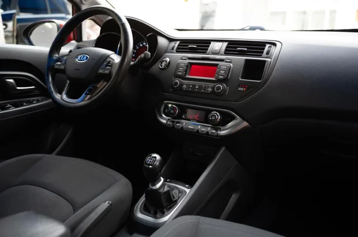 Interior of Kia Rio 2014 showing steering wheel, dashboard and manual gear lever of the 1.2 petrol rental car