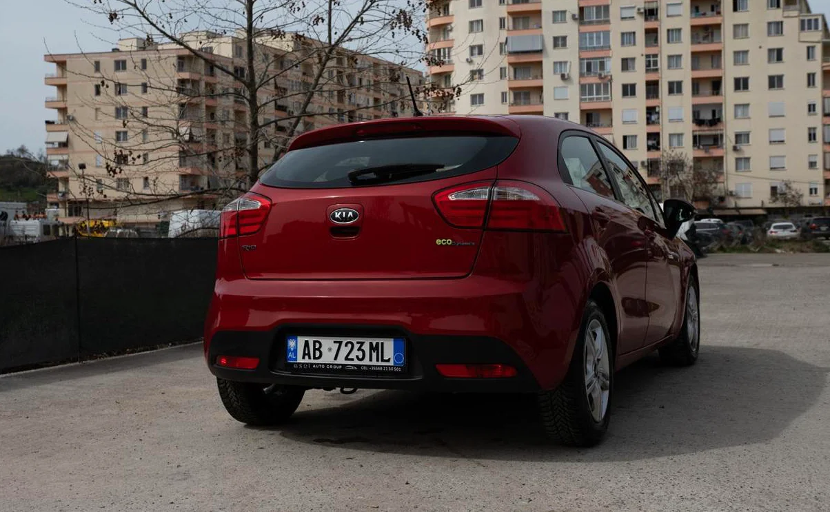 Kia Rio 2014 Rental in Tirana – 1.2 Petrol Manual City Car 37 - Car Rent in Albania Rear three-quarter view of red Kia Rio 2014 1.2 petrol manual rental car showing hatchback and Albanian license plate