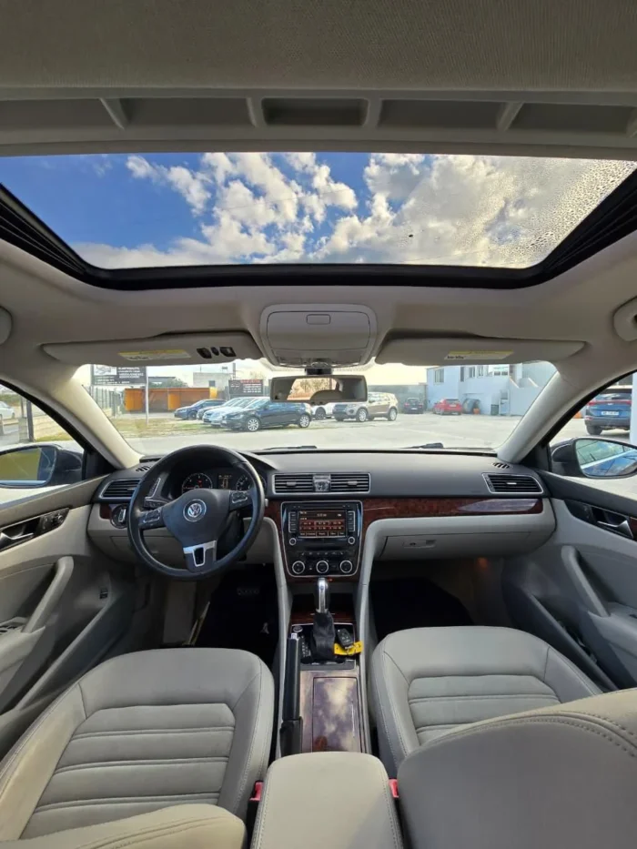 Interior of VW Passat SEL 2013 rental showing panoramic sunroof, beige leather seats, wood trim and automatic transmission
