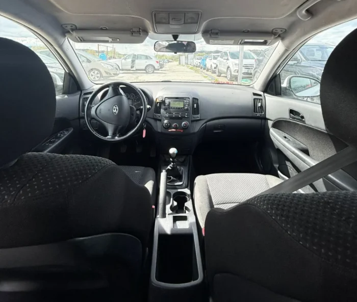 White Hyundai i30 2010 1.6 diesel manual hatchback rental car parked near Tirana International Airport Rinas with air‑conditioned interior