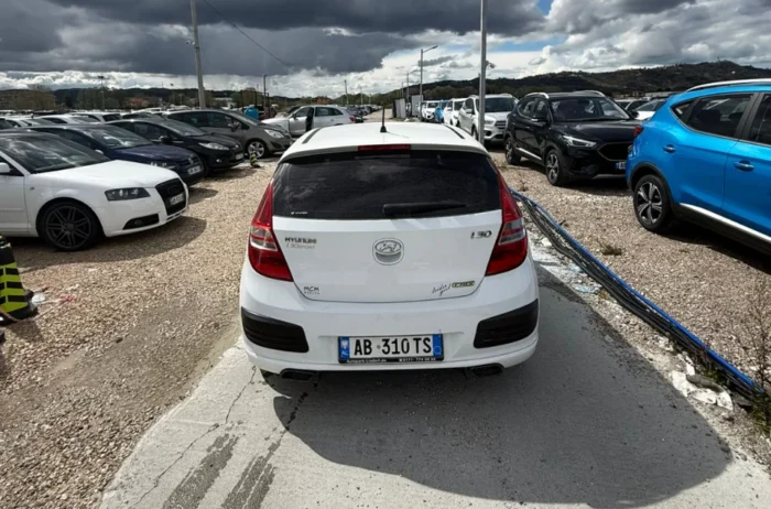 White Hyundai i30 2010 1.6 diesel manual hatchback rental car parked near Tirana International Airport Rinas with air‑conditioned interior