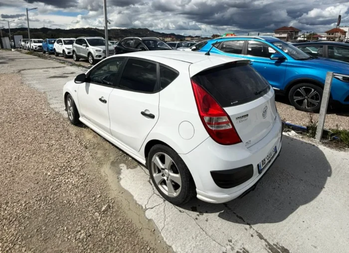 White Hyundai i30 2010 1.6 diesel manual hatchback rental car parked near Tirana International Airport Rinas with air‑conditioned interior