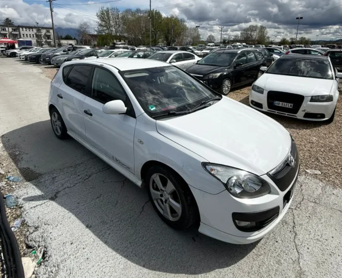 White Hyundai i30 2010 1.6 diesel manual hatchback rental car parked near Tirana International Airport Rinas with air‑conditioned interior