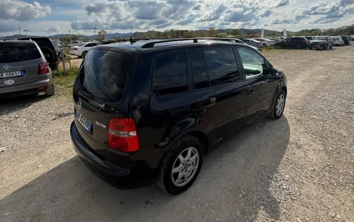 Black Volkswagen Touran 2008 2.0 TDI diesel automatic 7 seater MPV rental car parked on a gravel lot near Tirana International Airport Rinas
