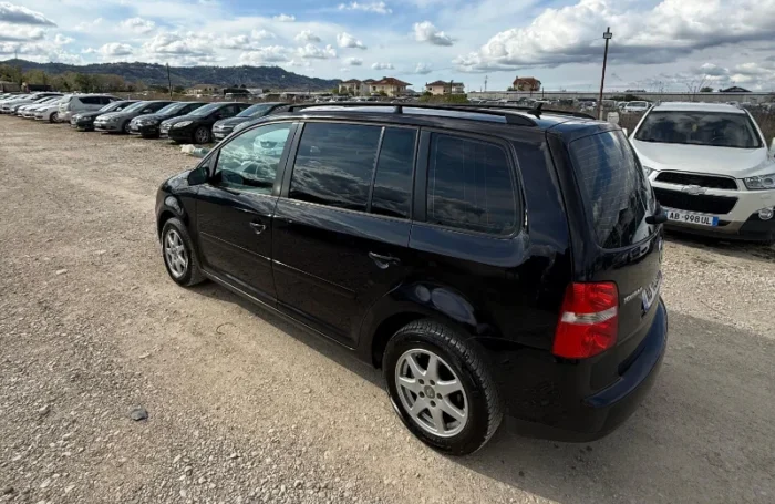 Black Volkswagen Touran 2008 2.0 TDI diesel automatic 7 seater MPV rental car parked on a gravel lot near Tirana International Airport Rinas