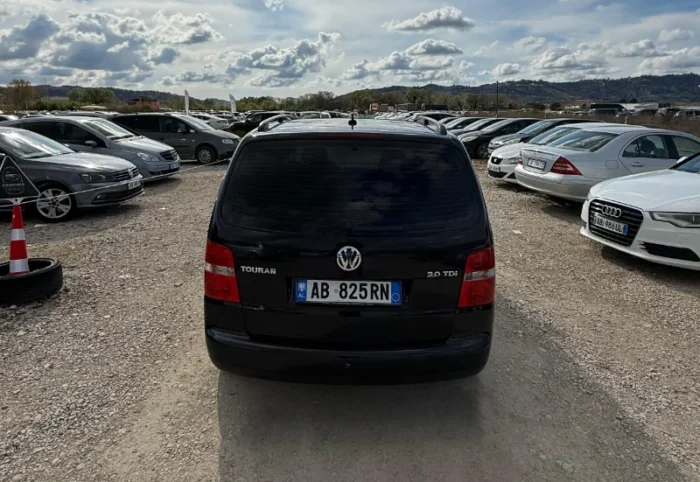 Black Volkswagen Touran 2008 2.0 TDI diesel automatic 7 seater MPV rental car parked on a gravel lot near Tirana International Airport Rinas
