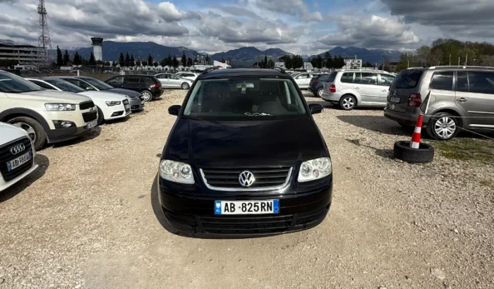 Black Volkswagen Touran 2008 2.0 TDI diesel automatic 7 seater MPV rental car parked on a gravel lot near Tirana International Airport Rinas