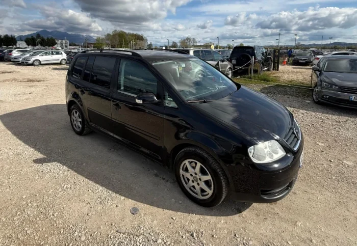 Black Volkswagen Touran 2008 2.0 TDI diesel automatic 7 seater MPV rental car parked on a gravel lot near Tirana International Airport Rinas