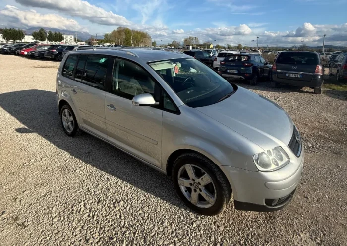 Silver Volkswagen Touran 2008 2.0 TDI diesel manual compact MPV rental car parked on a gravel lot near Tirana International Airport Rinas