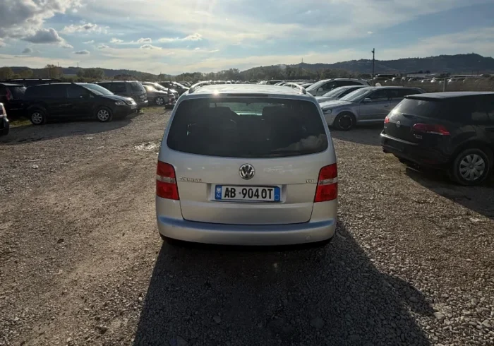 Silver Volkswagen Touran 2008 2.0 TDI diesel manual compact MPV rental car parked on a gravel lot near Tirana International Airport Rinas
