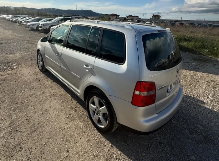 Silver Volkswagen Touran 2008 2.0 TDI diesel manual compact MPV rental car parked on a gravel lot near Tirana International Airport Rinas