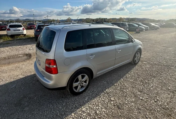 Silver Volkswagen Touran 2008 2.0 TDI diesel manual compact MPV rental car parked on a gravel lot near Tirana International Airport Rinas