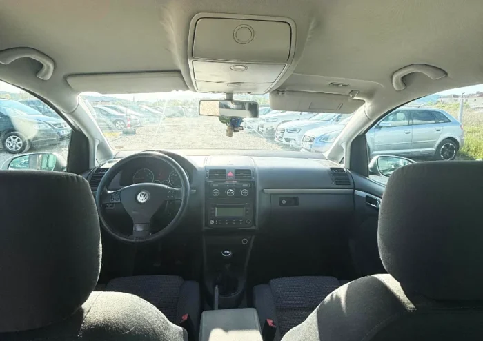 Silver Volkswagen Touran 2008 2.0 TDI diesel manual compact MPV rental car parked on a gravel lot near Tirana International Airport Rinas