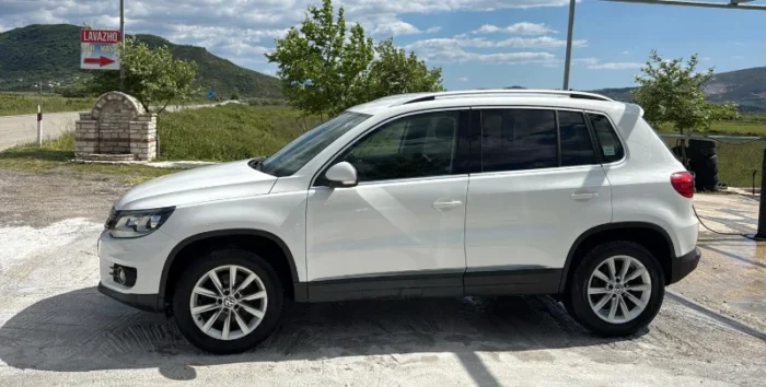 White Volkswagen Tiguan 2014 2.0 TDI diesel automatic 4x4 SUV parked in the Albanian countryside, available for rental from Tirana and Tirana Airport Rinas