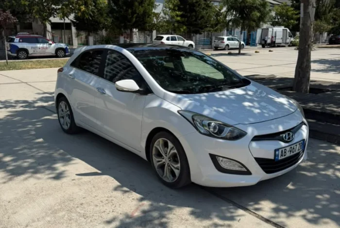 White Hyundai i30 2014 1.6 CRDi diesel automatic hatchback with full panoramic roof parked in Tirana, available for car rental in Albania with TiRental