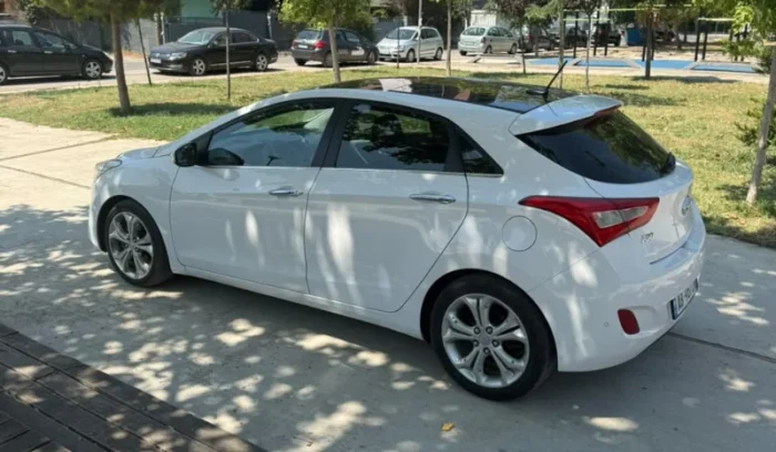 White Hyundai i30 2014 1.6 CRDi diesel automatic hatchback with full panoramic roof parked in Tirana, available for car rental in Albania with TiRental