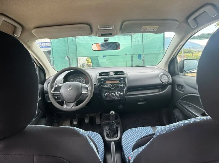 White Mitsubishi Space Star 2017 1.0 petrol manual 5‑door hatchback parked near Albanian mountains and Tirana Airport, available for car rental with TiRental