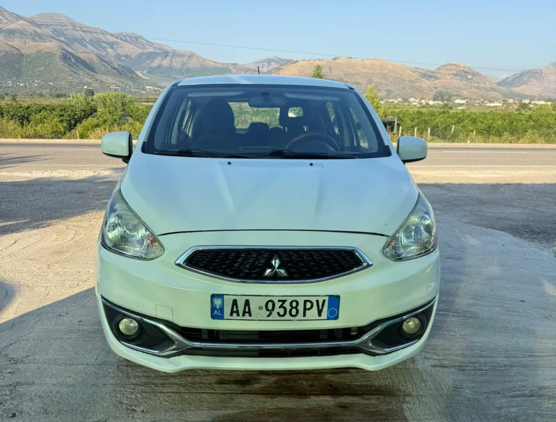 Mitsubishi Space Star 2017 - 1.0 Petrol Manual Hatchback Rental in Tirana Albania 30 - Car Rent in Albania White Mitsubishi Space Star 2017 1.0 petrol manual five‑door hatchback parked near Albanian mountains and Tirana Airport, available for car rental with TiRental