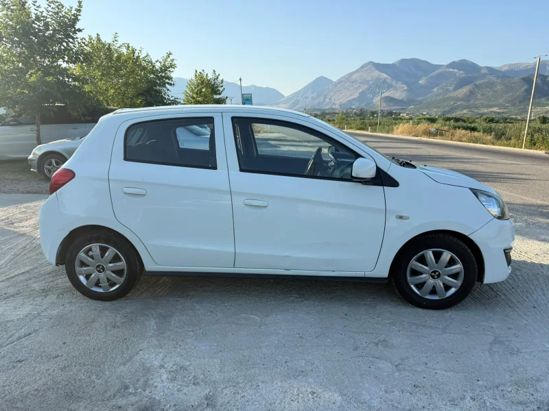 Mitsubishi Space Star 2017 - 1.0 Petrol Manual Hatchback Rental in Tirana Albania 28 - Car Rent in Albania White Mitsubishi Space Star 2017 1.0 petrol manual five‑door hatchback parked near Albanian mountains and Tirana Airport, available for car rental with TiRental