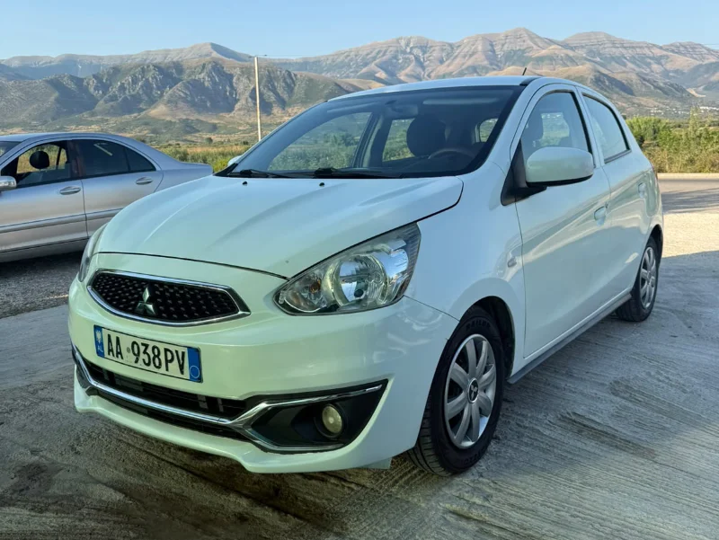 Mitsubishi Space Star 2017 - 1.0 Petrol Manual Hatchback Rental in Tirana Albania 26 - Car Rent in Albania White Mitsubishi Space Star 2017 1.0 petrol manual five‑door hatchback parked near Albanian mountains and Tirana Airport, available for car rental with TiRental