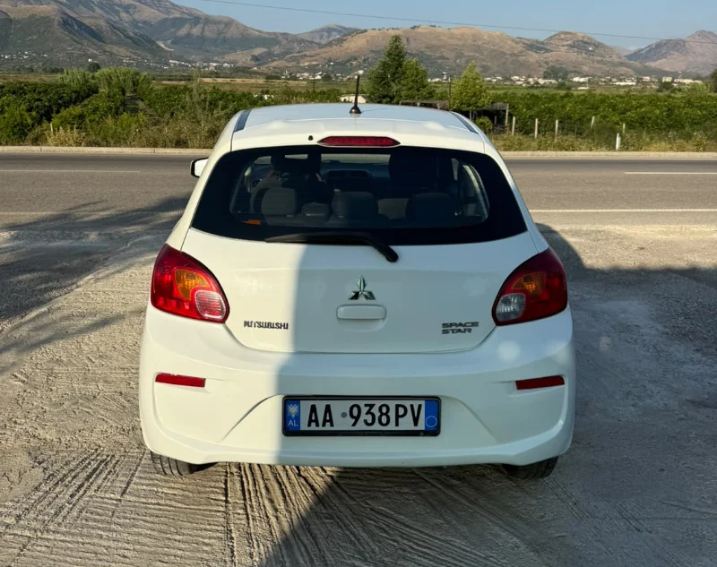 Mitsubishi Space Star 2017 - 1.0 Petrol Manual Hatchback Rental in Tirana Albania 31 - Car Rent in Albania White Mitsubishi Space Star 2017 1.0 petrol manual five‑door hatchback parked near Albanian mountains and Tirana Airport, available for car rental with TiRental