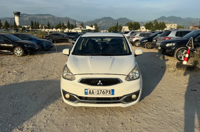 White Mitsubishi Space Star 2017 1.0 petrol manual 5‑door hatchback parked near mountains and Tirana Airport, available for car rental in Albania with TiRental