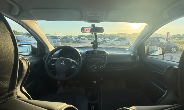 White Mitsubishi Space Star 2017 1.0 petrol manual 5‑door hatchback parked near mountains and Tirana Airport, available for car rental in Albania with TiRental