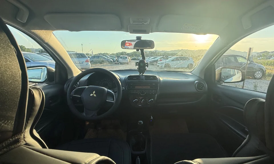 Mitsubishi Space Star 2017 - 1.0 Petrol Manual City Car Rental in Albania 19 - Car Rent in Albania White Mitsubishi Space Star 2017 1.0 petrol manual 5‑door hatchback parked near mountains and Tirana Airport, available for car rental in Albania with TiRental