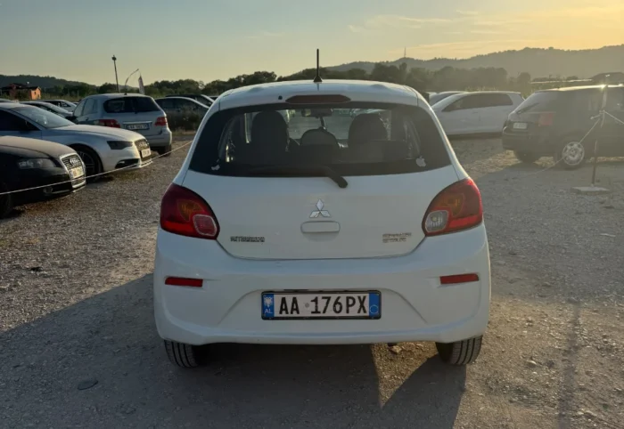 White Mitsubishi Space Star 2017 1.0 petrol manual 5‑door hatchback parked near mountains and Tirana Airport, available for car rental in Albania with TiRental